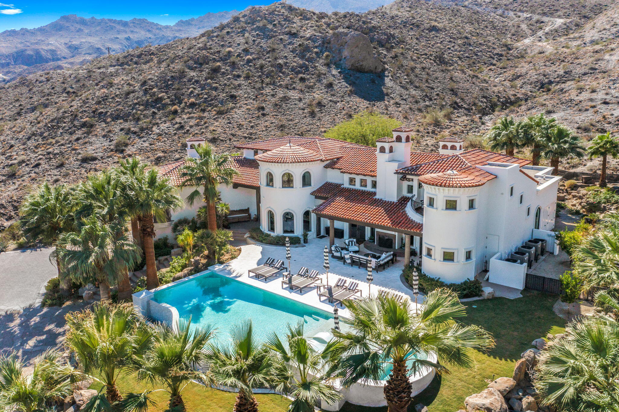 This breathtaking estate located in the South Palm Desert neighborhood of Cahuilla Hills offers dramatic panoramic views of the mountains, golf courses and down valley that are stunning day and night! Enter the secluded estate through the private gate, as you meander up the extended drive of the 2.39 acres set high up on the hillside you arrive at the spectacular 6,254 sq ft custom built estate. Walking up the dramatic entry staircase your eyes will be on overload as you see over 1,600 square feet of covered patios and balconies that surround the brand new huge infinity pool and extra large spa which is designed to let you enjoy an amazing indoor outdoor living experience day and night. The gourmet cooks' kitchen has been remodeled and will impress with its customization and huge island. The informal and formal spaces all have direct access to the outdoor living areas and boast beautiful hand carved stone fireplaces, forged iron railings, hand hewn beam trusses and wood floors along with rare natural stones throughout. The spacious primary suite has its own fireplace, sitting area and balcony making for a very relaxing retreat. The newly remodeled bathroom area has a unique round shaped shower and large soaking tub that comes with a view. The other three en-suites are separated throughout the two story estate offering the utmost in privacy and luxury. Add in the elevator and brick walled wine cellar making this a one of a kind property that is offered furnished per inventory.