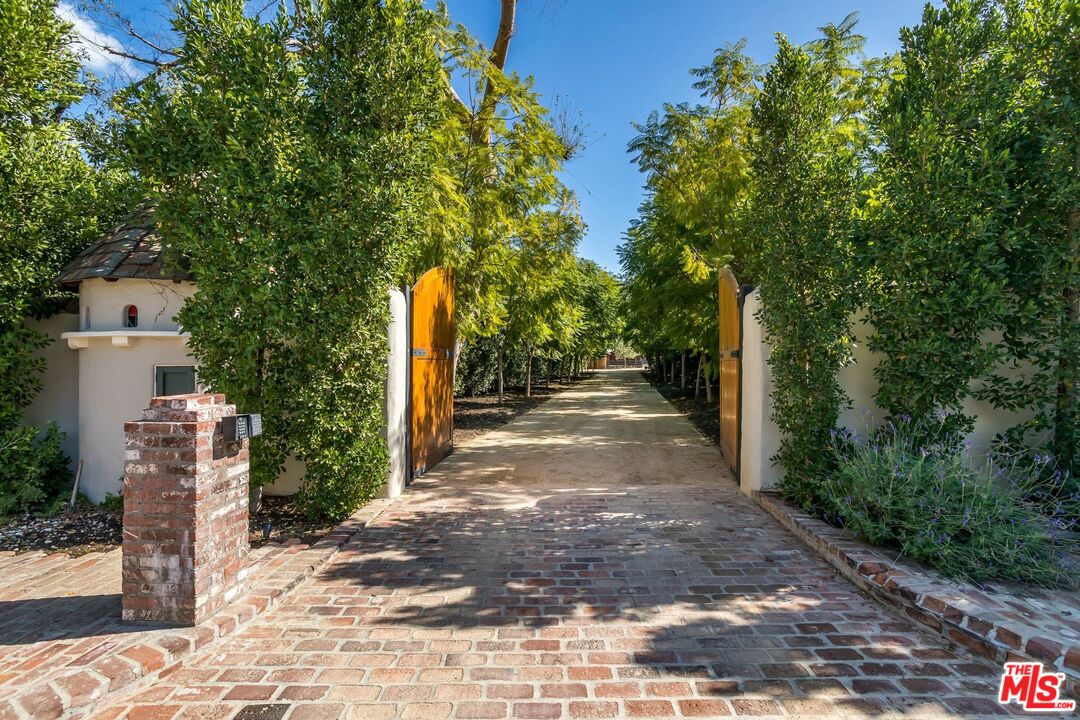 This sumptuous one-of-a-kind COMPOUND with multiple residences consists of 2 combined properties, encompassing 17407 RANCHO ST. The gated nature escape on almost 2.5 verdant acres features 2 MAIN RESIDENCES, 2 GUEST HOUSES, RECORDING STUDIO, BARN & BUNKHOUSE, POOL, SPA, SAUNA-RETREAT, CORRALS, AERIE, LIBRARY, PUB, BUTLER's KITCHEN, MAIDS & WORKSHOP. Beyond secure gates, a tree-lined drive leads to a private multi-family retreat that is easily accessible to bistros and shops, major studios, and LA's most highly rated schools. The 1930s main house has been expanded over time and is centered around an old-world style courtyard. On the main level, the light-filled living room dazzles with soaring ceilings and Venetian plaster walls. Entertain visitors in the original speakeasy pub or in the family room with its generous fireplace and artisan-crafted wood accents. The state-of-the-art chef's kitchen includes an expansive island, high-end European appliances, and a Butler's kitchen. The main house has 6 designer-done bedrooms, school room, and a studio with viewing terrace. A highlight is the courtyard featuring a fireplace and an ivy-covered arch that leads to a 20-metre length pool, spa and sauna house enclosed by mature foliage. Set amidst the lush acreage with its pond, bridges, water features and botanical gardens are 3 additional houses, including a restored 3 bed 1957 mid-century home outfitted with a world-class RECORDING STUDIO. The writer's cottage and the barn guest house are stunning with hand-crafted wood flooring and vaulted ceilings. A picturesque barn features a bunkhouse with horse turn-out.  (Listing includes two combined properties. Please view video for full breadth of grounds.) This extraordinary trophy compound, featured in the Wall Street Journal, is truly breathtaking.  (Seller financing available. Also available for lease. Kindly contact listing agent for details.)