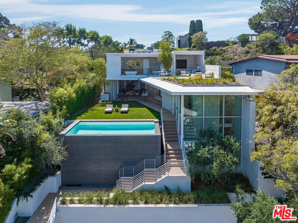 A stunning new build in prime Santa Monica, this residence was designed by the John Andrews Group, boasting a timeless modern style and a 6,200 square-foot, 4-bed, 6-bath floorplan across three levels. Arrive through privacy-enhancing gates and take in a generous foliage-lined driveway. Inside, find soaring ceilings, wide-plank white oak floors and bountiful contemporary design features and inspired amenities. Main-level living areas open to the grassy yard via automated Fleetwood doors. The kitchen is replete with Calcutta quartzite counters and Wolf, Miele and Sub-Zero appliances. On the home's second level is the spacious primary suite, which boasts a large balcony completed by multiple sitting areas and a firepit looking out to city light views. The primary suite's spa-like bath has heated, Italian-made floors and a free-standing soaking tub. Additional home features include an infinity pool, theater, bar, fitness studio, elevator and a two-car garage. Live amidst enchanting design and verdant scenery this special offering awaits.