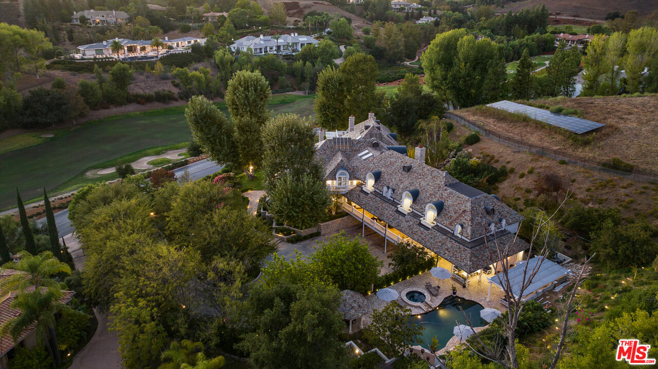 Over 3 acres of a French Country masterpiece privately gated in the exclusive community of North Ranch Country Club Estates. The idyllic mountainous backdrop with lush landscaping offers a home of elegant style and a peaceful ambiance. A grand entrance with a double height foyer and swooping spiral staircase features one of many walls of glass enveloping each room in natural light and expansive vistas views. The kitchen and living area give a nod to countryside design with beamed ceilings, wooden floors, and bay windows, to complement the intricate architectural splashes throughout. A magnificent primary bedroom with dual baths, walk-in closets, a cozy fireplace, and a seating area inviting you through the double doors to the storybook balcony overlooking the grounds. The 8-bedroom, 10-bath house is complete with a formal library of carved wooden detail, a workout room, a classic stone wine cellar, a state-of-the-art theater, and a bonus/game room. The outdoor oasis, both functional and organic, is anchored by a custom pool and spa with cascading waterfalls. An outdoor kitchen, entertaining areas with TV and speakers, a gazebo, and acres of land all enhance the enjoyment of a magnificently landscaped compound in one of the most sought-after neighborhoods in the country.