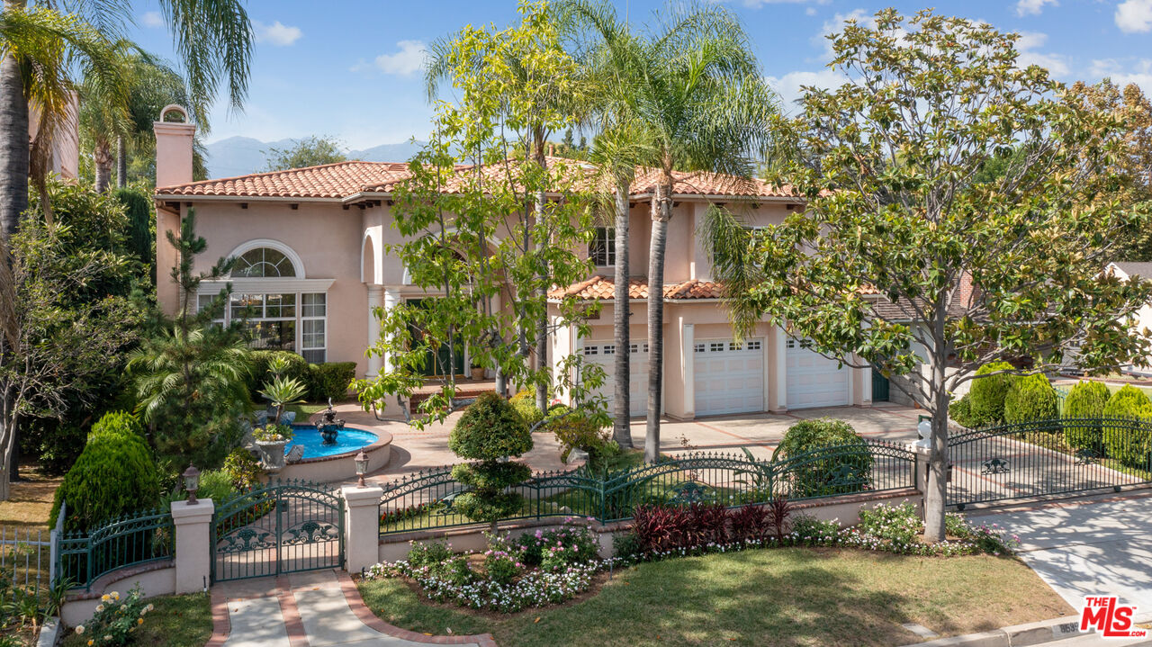 Located in the San Marino School district, this impressive two-story estate exudes pride of ownership and sits on an expansive resort-like lot. The private gated driveway is surrounded by mature landscaping, custom hardscaping, and a water fountain. The arched covered entrance showcases ornate double doors which open to the high-vaulted ceiling foyer with a sparkling crystal chandelier and an elegant semi-circular staircase. The step down living room adorned with large arched windows flanking the marble fireplace showcases an 18 foot ceiling that sets the tone for this breathtaking residence. Through the farge pillar lined archway one finds the formal dining room which is graced by a gorgeous chandelier and contains a set of French doors that lead to the captivating backyard. The private oasis has a koi pond, a waterfall feature with stone bridge, pergola, pool, spa, and beautiful landscaping which is perfect for relaxation and entertaining of any size. The formal dining room adjoins the 'great room' which is the heart of the home. On the West side lies the chef's kitchen; featuring white cabinets with striking granite countertops, top of-the-line appliances, an island equipped with a prep sink, snack zone, and spacious walk-in pantry. Next, the casual dining area between the kitchen and family room encompasses gorgeous backyard views through light-filled French bay windows and a French door leading outside. The East side of the great room is topped off with a family room anchored by a fireplace and a built-in wall-to-wall entertainment center. Completing the first floor is a powder room, guest suite with full bath, laundry room, and access to the 3-car garage. Ascending the sweeping staircase one is greeted by a built-in wet bar station with fridge, display shelves and a tray ceiling. To the left of the landing is the luxurious primary suite with home office, amazing views of the backyard, ensuite bathroom with dual sinks, jacuzzi tub, separate shower, water closet, and two custom walk-in closets. To the right of the landing contains the rest of the sleeping quarters; 2 junior bedrooms that share a full bathroom with dual sink and another large bedroom suite with views of the front yard and its own private dual sink full bathroom. Other noteworthy features include: double pane windows, recessed lighting throughout, dual HVAC systems, and copper plumbing. This sophisticated and well maintained residence truly exemplifies California living at its best!