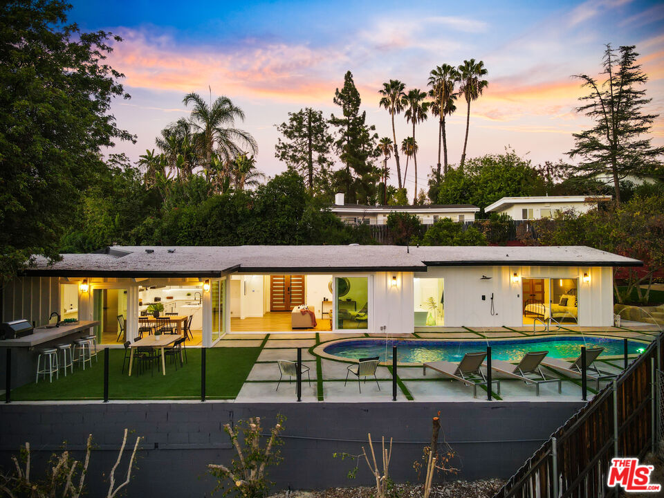 4670 Brewster Dr Tarzana, California Opportunity to strike a Breathtaking Midcentury Modern style Stunner Home featuring gorgeous Panoramic Sunset & Tree Views South of Ventura Blvd! Situated high up on the Hill, this tastefully remodeled house takes full advantage of its Premier Perch. Enter into a bright, spacious & hypnotizing living space largely open to the backyard & highlighting stunning chandeliers & light fixtures & a surround sound system all around. You'll notice the lovely open concept between the living, dining and kitchen spaces creating an incredible flow that will take your breath away with their unforgettable details. As the heart center of the home, the main living spaces are bathed in light and exude a warm welcoming vibe with a central electric fireplace perfect for family gatherings. The kitchen features stunning cabinets, captivating gold finishes & pendants, brand new stainless steel appliances, loads of storage space, gorgeous decorative shelves, a breakfast nook in addition to a large envious island perfect for your event Buffets. Large sliding glass doors & windows all around offer a very relaxing indoor-outdoor atmosphere leading to a stunning large pool with amazing water jet features, a fully equipped large BBQ Bar all looking into jetliner mountain & greenery views. The office offers a beautiful floor to ceiling window design and the hallway bathroom takes you on a Getaway Dream with its gorgeous Moroccan tiles. The Master Suite is one to die for! Wait till you see it.. The enormous & gorgeous entertaining backyard with its BBQ Bar, dining area, large firepit area is just perfect to step and relax outside & enjoy the amazing views. It offers plenty of room for large unforgettable family & friend gatherings, large special events, play... Neighborhood attractions include El Caballero Country Club, High end Golf courses, Marvin Braude Mulholland Gateway Park, Ventura Blvd and easy access to all the Best Shops & Entertainment! Very close to all the Freeways. Not to be missed!