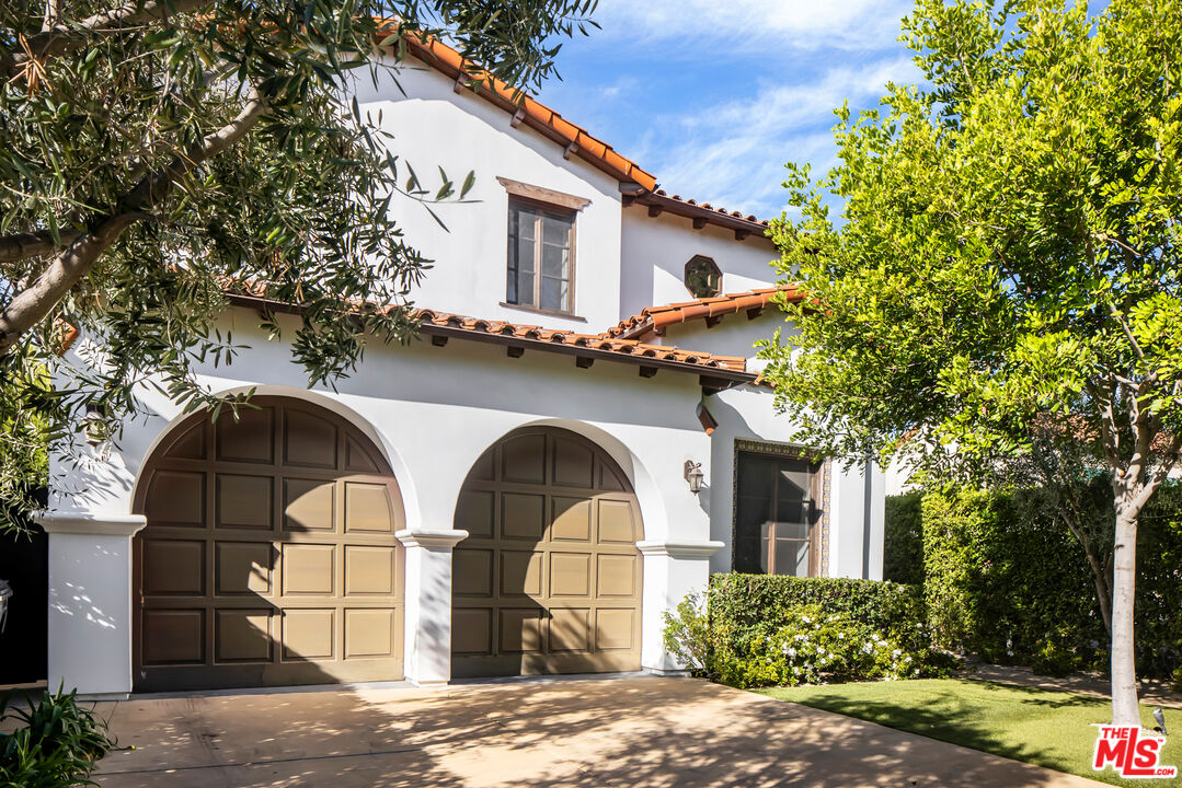 Montecito aesthetic in Beverly Grove! This custom-built gated 4400 sf Spanish gem with 4 b/b is a true California dream. Upon entering the classic home, you are greeted by a two-story foyer with a grand staircase and glimpses of graceful archways and architectural details bathed in natural light. Featuring a truly ideal floor plan, the foyer opens into a large living room that includes a contemporary fireplace, high-pitched beamed ceilings, and views to the backyard. The adjacent formal dining area is situated next to a fantastic entertainer's kitchen outfitted with Viking appliances, granite counters, and an oversized island. Both the living and dining rooms provide direct access to a stunning, one-of-a-kind private yard that has been featured in numerous magazine shoots. An elegant covered dining and living area, with a beautiful fireplace allows for seamless indoor/outdoor living. The pool and spa, with gorgeous Spanish tiles, a stunning water feature, and new outdoor kitchen with barbeque, complete this entertainer's paradise. The second story, built around the beautiful entranceway, has three oversized bedrooms and ensuite bathrooms, two of which are dual primaries. A large walk-in closet and balcony adorn one of the primary bedrooms, while an alcove/ sitting area off the second primary offers the perfect place to lounge. The third bedroom and bath also features a large closet and balcony access overlooking the pool and patio area. Washer/Dryer is conveniently located on the second story. Downstairs, the fourth bedroom can easily be converted to den, office or playroom. A true two-car garage with direct access to the kitchen along with two parking spots inside the gated driveway provides ample parking. A great neighborhood within walking distance to the Grove, Beverly and Third Street shops and restaurants, and Melrose Ave. make this beautiful house a tranquil oasis with all the urban amenities nearby.
