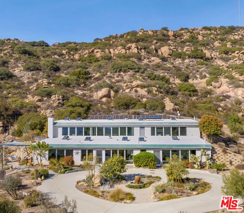 Never before has Southern California seen such an architectural, environmental and sustainable home hit the market. Known as an "Earthship," as designed by world-renowned architect and Earthship inventor Michael Reynolds, The Earthship at 7401 Studio Road was built to take advantage of the existing natural phenomena of the earth and sun. This 2 bedroom, 2 bathroom earth-sheltered property, with panoramic south-facing views, is built into the natural hillside and autonomously relies on the ambient temperature of the earth, passive solar heating, and air convection through 10 operable skylights, to heat and cool itself naturally. The property boasts over 3,600 square feet of ecologically-informed perfection spread over 88,080 square feet of grounds, thoughtfully landscaped with varieties of indigenous, drought-tolerant species.  The floor plan delivers additional uses of space, including an open kitchen, sunlit grand room, central office/den and a functional guest room. A detached 2-car garage is ideal for housing vehicles, personal storage and a creative setting for a music, art or meditative studio.