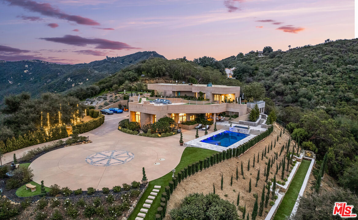 This incredible contemporary estate is unlike any other - with over 37 acres of privately gated secluded bliss. Set among the breathtaking beauty of the Santa Monica Mountains, this state-of-the-art home boasts spectacular 360-degree views, making it the perfect choice for even the most high-profile clients.  As you enter through the impressive lighted waterfall gates, you'll immediately notice the eternally luxurious feel - this spectacular property features parking for over 30 cars, a rooftop deck that will take your breath away, and a luxurious pool and spa that's sure to keep you relaxed and refreshed. From the gleaming hardwood floors to the curved glass walls, this home boasts the finest finishes available.  Inside, you'll find a peaceful koi pond and two immaculate fireplaces. With patios and expansive windows providing "forever" views of the stunning Santa Monica and Santa Susana Mountains, every detail feels like perfection. Each bathroom features an art-deco flair and has been crafted using only the highest quality materials.  Of course, no dream home would be complete without an unforgettably impressive gourmet kitchen - this property boasts two prep stations, a center island, stainless steel fridge, and a Viking stove, making it a must-see for even the most demanding cooks.  With its captivating design and perfect layout for hosting larger events, this property feels like the ultimate escape. And if that's not enough, you'll also have access to a private helicopter landing pad, a state-of-the-art wildfire suppression system, and a concierge firefighting strike team, making sure that you'll always feel comfortable and safe.  Finally, this remarkable home has been constructed using poured-in-place concrete, making it a true architectural masterpiece. With additional acreage that's perfect for additional ADUs, there's no better choice for discerning homeowners who are looking to make a statement.