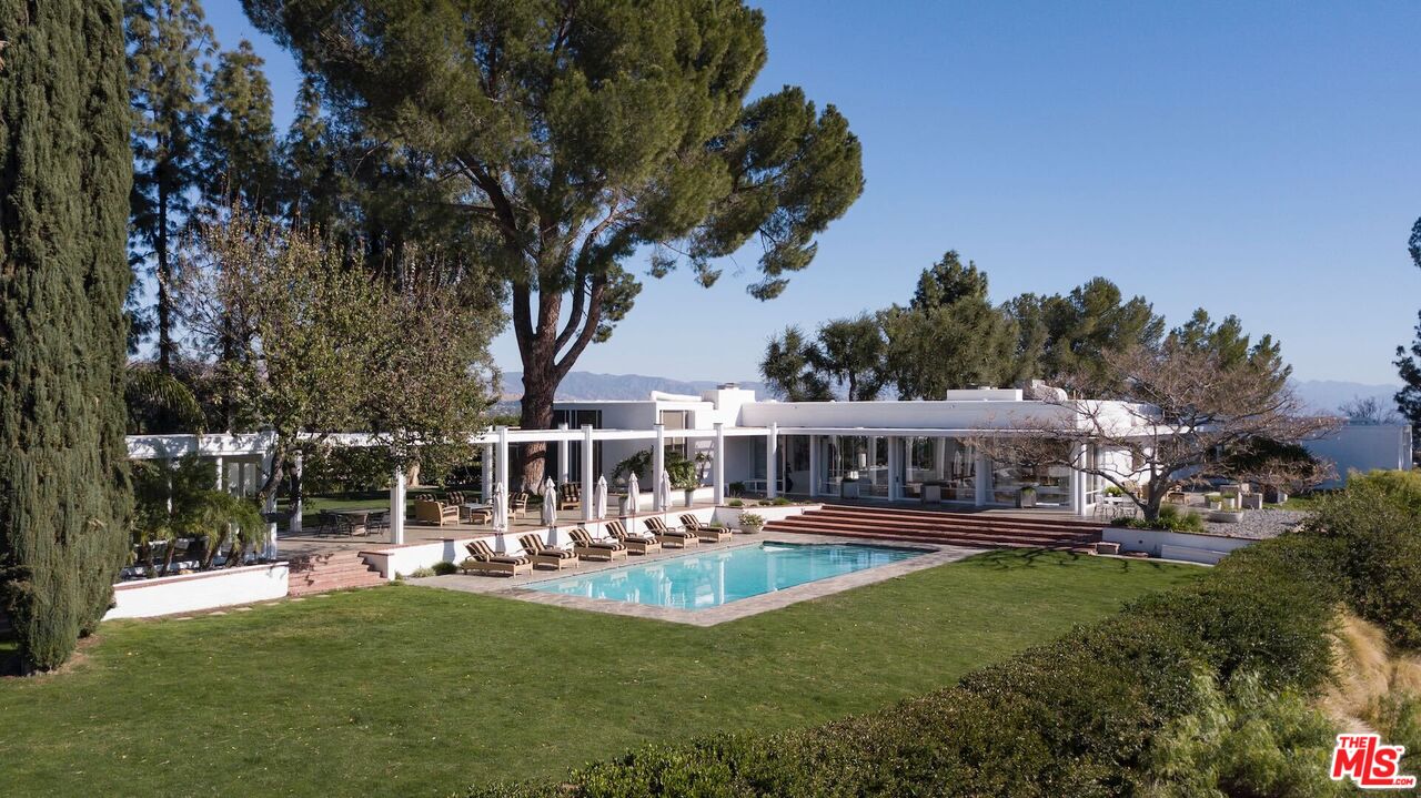 9216 Farralone Pl Chatsworth, California The Farralone House, a masterpiece by William Pereira, FAIA. A half-mile proprietary road sweeps you up to the private restored masterpiece of glass-walled pavilions seamlessly embracing the almost 4 flat acres of pine-studded grounds and the panorama of the 1,325-acre meadowlands of Lake Chatsworth nature preserve. Beyond, the Santa Monica, Santa Susanna, Verdugo, and San Gabriel Mountains frame the 360-degree view of the communities of West Hills, Hidden Hills, and Calabasas and all the way to Universal Studios. A broad ambulatory leads guests to the center pavilion revealing the major proportions of the residence with its 16-foot ceilings, luminous white walls and floors. This entry gallery leads them directly through giant sliding doors to the 50-foot pool, lounge terrace, and the pergola. Flanking the entry pavilion are the grand parlor or living room with zebra cork floors and a separate master suite and wing. The dining room, kitchen and three ensuite bedrooms with sitting room comprise the westerly structure. The arcaded pergola, a modern cloister, directs one to the pool house/cabana/gym. Either of two walkways meander to the sequestered one-bedroom guest house with its own pool.The complex totals five bedrooms, six and a half baths, and two kitchens with approximately 15 acres of grounds and a huge motor court. Ripe for equestrian retreat, vineyard, or tract map potential on part of property.The residence, guest house and pool are replete with Hollywood lore, from Francis Lederer, Judy Garland, Lucille Ball,Sinatra, Monroe, and a lore that continues with the site's vaunted film/video locations. (See links to examples below.) More than his masterpiece, this property may be Pereira's culmination of residential design. It is truly a "One Of A Kind" home.