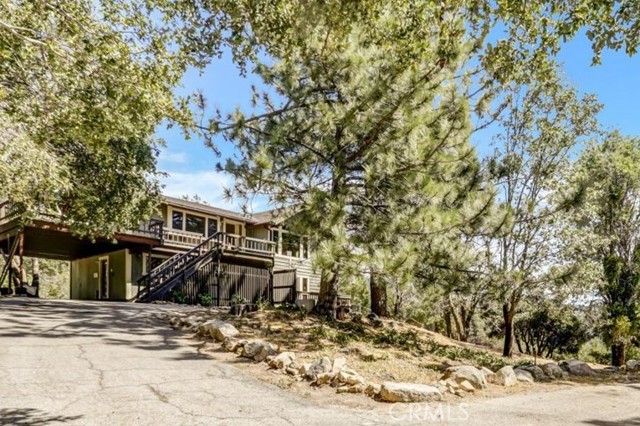 Views and privacy galore! This 3 bedroom 2 ½ bath mountaintop home with views from every room was built in 1981 and is approximately 2,542 sq. ft. This rustic horse property sits on 4.33 acres in the highly sought after Dart Canyon and backs up to a National Forest.  Scenic horseback trail rides all around you!  Saddle up and instantly enjoy secluded trails, no trailering needed.  The property features expansive rolling hills and flat grounds with a large open horse arena, tack rooms, horse stalls, sprawling trees and tons of parking for horse trailers, toys, your large family and/or events. Interior highlights include large picturesque double pane windows, two ac units, wood beams and paneling, and many custom built ins throughout. The entire second floor is open concept with family areas perfect for gatherings and a half bath for your guests. Features include a large kitchen with pantry, spacious welcoming dining room that leads out to a sizable wrap around deck with grand views of the entire property and a bright and beautiful living room filled with high wood beamed ceilings, a fireplace and giant windows featuring more stunning mountain top views. There is also a reading nook or potential office area with sliding door access to a large fenced in dog yard perfect for your pets. The first floor hosts all 3 bedrooms, 2 baths, and a laundry room with tons of storage. The large master suite includes a walk-in closet, custom built ins, generous sized bathroom with giant jacuzzi tub to soak in while you soak up the mountain views, and a private deck perfect for your morning coffee or watching the starry nights. Enjoy your own private hideaway retreat less than 10 minutes from Lake Gregory, shops, and restaurants. Walking trails, horse trails, hiking, and fishing also close by. Oh, and don't be surprised if you happen to spot a deer or two as you explore the grounds on this beautiful forested estate!