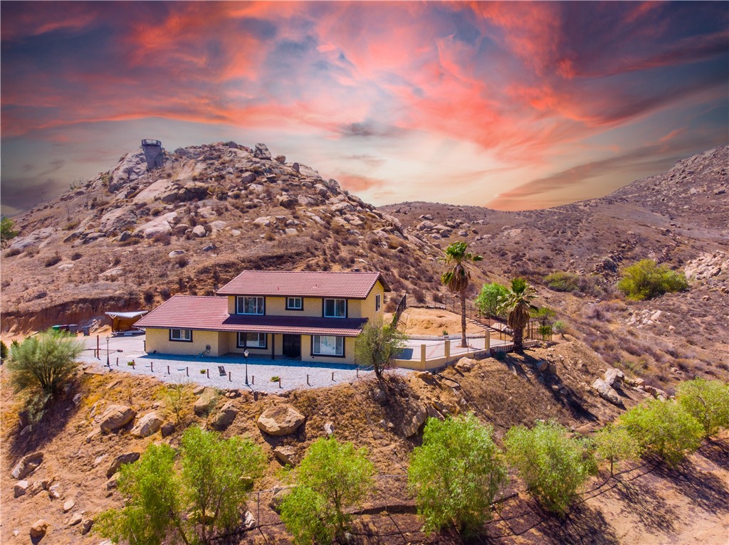 This quintessential "House on the Hill" is only going to be available for a very short time. So, take a good, hard look at this one. Situated atop the perfect oversized pad on a beautiful bluff with arguably one of the most majestic 250 degree views in the valley. It is awe inspiring. If the view isn't enough, you'll love the privacy this home offers on almost 2 acres. You would have to yell pretty loud to greet any of your neighbors. The gated entry off of the paved country road leads you up a long driveway. Down below the home is a large (nearly an acre) plot of gated land, ready for horses or an income-earning ADU. You also own a part of the hill and massive boulders behind the property. It's a fun climb and the neighbor has built a look-out deck to capture the beauty from up there. There's nothing stopping you from doing the same. On the west side of the home is an enormous slab-patio area with great views, ready for big parties and entertaining. It's an efficient home too with its own well / water supply, a 26 solar panel set up (paid-off) and propane. It has plenty of room for RVs and even to add a fancy pool.  The house itself is in great shape. The kitchen was remodeled not too long ago, the carpets are in very good condition, there is a large family/bonus room downstairs, a living room with a stone (wood-burning) fireplace, wooden beam ceiling, a home-gym with padded flooring and French doors to the backyard, a large master suite with a big remodeled bathroom and the ideal, spacious, private deck. The other bathroom upstairs is remodeled too and has a high-end mirrored glass (reflective) sliding shower door. It's pretty neat. Truthfully, this home is clean, move-in ready and very simple. The view and the property are the highlights. However, it wouldn't take much to make the house pop! All the basic elements are there. Just bring your interior designer and fresh palette to make 11425 Tiffany your dream home. Need more convincing? Come see it with your own eyes. This one TRULY won't last.