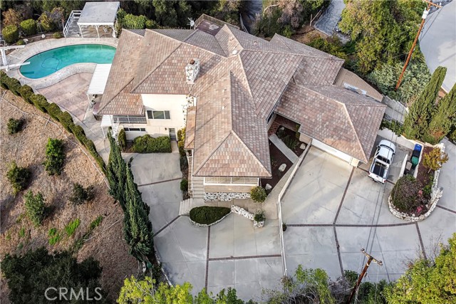 Located at the end of a private cul-de-sac, this one of a kind Estate sits on one of the largest private parcels in the area. Relish in the stunning panoramic views of Los Angeles from almost every room of the house. This gorgeous tri-level Estate sits on 2.3 acres & is an entertainers dream. Ample parking for all your guests, a 2-car detached garage, a sparkling pool with private deck & even a gym, a pool house, or a separate ADU that is attached to the main home on the bottom floor. If you love trees or are an animal lover, explore all the possibilities with approx. 30 avocado producing trees & too many various fruit trees to name but close to 47 along with a horse barn and a gated dog run located just off the back of the garage. Truly a house that meets all your family's needs. Enjoy 7 Bdr's & 6 Ba's, a Terrazzo floor entry, a Flagstone floor to ceiling corner Fireplace, a step-down plushly carpeted formal living room that is accentuated with vaulted wood paneled ceilings complimented by a unique wood inlay design. Access your centrally located covered balcony just off the sliding glass doors of either the living or dining room, perfect for BBQ's or watching the sun set over LA. Walnut colored hardwood floors line the kitchen, dining & family room. Chef size kitchen with island & corner pantry along with separate breakfast nook, all with lots of cabinet storage. Separate library with walk-in closet could also be 8th Bdr.  3 Bdr's & 2 Ba's upstairs, 2 with full baths & one rectangular Bdr that could be used as a baby's room, sewing or crafts room. Downstairs, 2 large Bdr's one with attached bath, an extra large entertainment room & kitchenette along with laundry area (complete w/Laundry shoot), & separate 3/4 utility room bath with cedar lined walk-in closet. It's the perfect pool house retreat or to have extended family stay in their own private area with their own resident access. Gated sparkling pool just out back & a separate gate to access fruit trees & all the other parts of the property, truly surprises around every corner. Some other features include a whole house fan, central vacuum system, copper plumbing & so much more.  This is a must see!