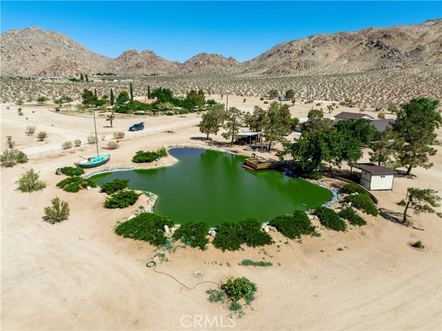 BACK ON THE MARKET AT NO FAULT TO SELLER! GORGEOUS Ranch Property with a 1/3 acre private pond, private well, and 40 USEABLE ACRES!! Located in the Cove in Lucerne Valley with PANORAMIC VIEWS! This unique property has SO much to offer! The home boast at just shy of 3,000 Sq Ft with a wrap around porch, a 2 car attached garage, detached 900 Sq Ft workshop, greenhouse area, barn, 80 Ft in diameter arena, 3 horse stalls, fully loaded outdoor kitchen, oversized fire pit, and fishing/ tack room! To top it all off this incredible property has a BEAUTIFUL 1/3 acre, 7ft-8ft in depth, pond that is stocked with mature Blue Gill, Catfish, and Koi with a large dock, AND fountain feature! Throughout the home you will see pride of ownership in every corner! The brand new flooring throughout is welcoming with the cozy wood beamed ceilings, wood burning stove, bonus room/ den area, large kitchen with a walk in pantry and brand new built in appliances! The formal dining room is large enough for the WHOLE family, with oversized bedrooms to accommodate! The master bedroom has a walk in closet WITH A FLOOR SAFE! The bathrooms have both tubs and stand in showers and well as an abundance of storage throughout the ENTIRE HOME! The dual pane windows throughout open up to the panoramic views this home is surrounded by! The exterior of the home is nothing less than impressive, with a wrap around porch, lawn with all new irrigation throughout, large courtyard off the back, mature trees including 8 pistachio trees, and approx 4 acres fully fenced! This property is what dreams are made of! Seller is MOTIVATED! Come see this forever home today!