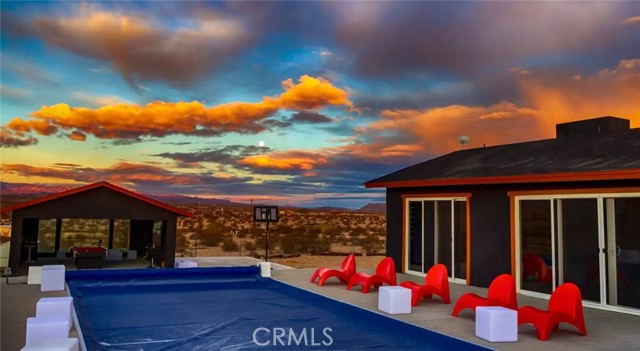 Amazing opportunity for you to own this unique ultra-modern 4 bedroom 3 bath Joshua Tree home with built in pool. This home is a high producing Airbnb short term rental. Situated in the world famous North Joshua Tree area with sweeping views of the valley below. This 2.5 acre property is situated next to 5 acres of government land to the south and 2.5 acres of government land to the west so you or your guest will feel like you are in the middle of a desert oasis and star gaze at night while you relax in the modern pool. Home features an outdoor shower, unique epoxy flooring throughout the home and countertops, dual master suites with private bathrooms, indoor laundry with stackable washer and dryer, kitchen features stainless steel stove, refrigerator, dishwasher and microwave. All appliances and furnishings are included so you can just move right in or continue with the income producing short term rental. Detached garage has been converted to a game room with multiple tv monitors and pool table. Electric car charging station included as well as all the outdoor furnishings. The modern style built in pool offers new equipment, electric powered pool cover and modern cement decking with acid wash finish really makes this home a perfect getaway retreat. Do not mis out on the opportunity to view one of Joshua Trees unique properties. Call now and schedule an appointment so you can see for yourself before it's too late and the opportunity is missed.