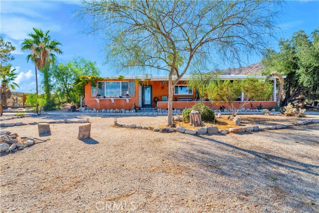 ***CLOSE TO JOSHUA TREE NATIONAL PARK*** Located just 3 homes from the Joshua Tree National Park boundary, this beautiful home is suitable for full-time living or vacationing. Hike into Joshua Tree National Park at the end of Twilight Drive.  This 1955 charmer is situated on 4.6 view acres, and features 3 bedrooms and 2 bathrooms.  Along the front of the house is an expansive covered porch, with long views of the town and the Bullion Mountains to the north.  Flanking the house is a large, detached garage/studio/shop building (937 square  feet) that is finished inside, with white drywall, insulation and evaporative cooling. The great room of the main house has beautiful open-beam ceilings with view windows and glass doors.  There is a wood stove in the great room for cozy winter nights. The house is U-shaped, with a private courtyard patio and private garden, including an in-ground hot tub.  The private garden has beautiful views of the Mountains of Joshua Tree National Park.  The hot tub is an excellent place to relax in the peaceful garden and enjoy the amazing starry skies above.  Recent renovations of the home include a complete remodel of the master bathroom, new Milgard windows throughout the home, new exterior doors, smart garage door openers, a new refrigerator and new dishwasher.  The house has ducted heating and central air conditioning.  It also has mini-split air conditioning, heating and evaporative cooling.  Hot water is provided by a newer tankless, on-demand water heater.  Local amenities are also nearby and include the vibrant shops and restaurants of downtown 29 Palms, the Tortoise Rock Casino, the Sky s the Limit Observatory and the national park headquarters with a visitor center and the main entrance to the park.