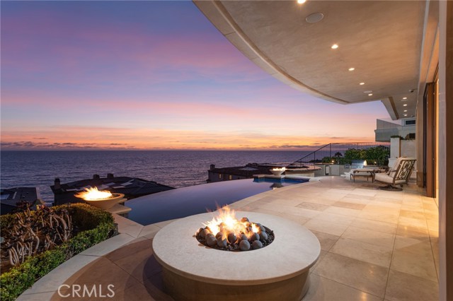 When only the best is what you desire, your search for the ultimate seaside sanctuary will end at this sublime custom estate at The Strand at Headlands in Dana Point. Indoor/outdoor living reaches new heights thanks to grand exterior spaces for splendid entertaining that include a main terrace with a sparkling vanishing-edge pool and spa, fire bowls, a fire pit and an outdoor kitchen with grill. An elevator with window accesses all levels of the residence, including a rooftop patio with BBQ and fire pit. Of course, nearly all areas of the home are enriched by spectacular ocean views that span breaking waves, colorful sunsets and dramatic bluffs. Indoors, floor-to-ceiling windows and slide-away glass doors bathe the home in natural light throughout a luxurious floorplan that extends approximately 8,339 square feet and hosts four ensuite bedrooms, six baths, a 15-seat Dolby Atmos theater, wine cellar and a fireplace-warmed library. A secondary suite displays a Juliet balcony, and the lavish primary suite of nearly 1,700 square feet shares an ocean- view deck with another bedroom and features a sitting room, linear fireplace, granite finishes, a steam shower, skylight, tub, two Toto toilets and dual walk-in closets. At the heart of the home, a magazine-caliber kitchen is appointed with an oversized island, walk-in pantry, custom cabinetry, stone countertops and high- end appliances including a built-in coffee station and two steam ovens. The kitchen opens directly to the dining and great rooms, creating a spacious and airy setting for entertaining in style. Meticulous craftsmanship complements a design that is highlighted by dramatic ceilings, natural stone and wood finishes, limestone flooring, curvilinear walls, elegant chandeliers, custom built-ins throughout, a subterranean six-car garage, two laundry rooms and solar power. Residents of The Strand enjoy a guard- gated setting with private amenities that include an oceanfront beach club, Strand Beach, 70 acres of open space and three miles of coastal trails. Noted as the last new-home enclave along Southern California's world-famous coast, The Strand is close to high-end shopping and dining, Dana Point Harbor, recreation and so much more.