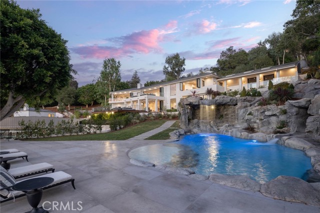 The ultimate in luxury, privacy and scale is on display at this completely remodeled, gated Beverly Hills compound featuring nearly 14k square feet of living space, 1k feet of decks and sitting on 1.7 acres of land. Nestled in the highly-coveted Oak Pass Road Gated Community this home has been designed for the discerning buyer who wants it all. The property offers a huge main house, two story guest house, separate 3000 sq ft gym, full sports court, resort style pool with waterfalls, waterslide and grotto, full outdoor kitchen with wood-burning pizza oven, motor court, 3 car garage, putting green and much more. The main house features 5 bedrooms and 8 bathrooms showcasing natural light, walls of glass and full smart home automation by Savant. The brand new chef's kitchen has Wolf and SubZero appliances, beautiful new marble counter tops, climate controlled wine storage and huge, bi-fold windows for indoor-outdoor living. Invite friends to enjoy your favorite movies in the fully equipped theater with 136  screen, wet bar and wood burning fireplace. The primary suite offers calming canyon views from a wall of sliding glass doors, fireplace, his/hers bathrooms with gorgeous marble slabs, aromatic oil & steam showers, private staff entrances and hair salon. Multiple living areas offer opening walls of glass, views, high ceilings, white oak wire brushed wood floors and beautiful finishes throughout. Family and friends can relax in the 2 BR / 3 BA, 2 story, well appointed guest house with full kitchen and private patios. The stand-alone gym is like your own private Equinox with 2 levels of equipment and full size boxing ring. The beautifully manicured grounds, citrus trees, fire pit, multiple water features, captivating views and more will make you feel like you re at a resort as you stroll the property. No expense was spared to create a constant feeling of luxury and privacy. Come and experience this one-of-kind showpiece today.