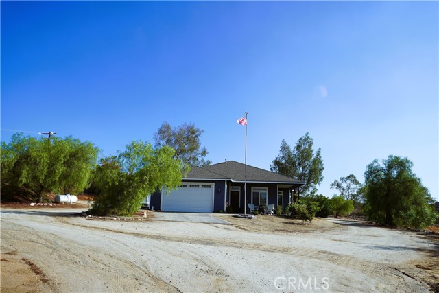 Come out to the country in this quiet neighborhood. Nuevo is a small town with a big heart not far from Perris and Hemet. Shopping and Lake Perris are only 15-20 minutes away . Plenty room to roam with 2.6 acres, bring your horses and critters for a small farm. This 3bd and 2bth home has 10ft. ceilings that give a spacious feel. The kitchen is open design with granite counter tops and raised bar. In the family room is a fireplace that makes the home cozy. For that someone who likes to work on vehicles, there is an attached garage and a 19x30 workshop. The workshop is equipped with an outlet for welding or RV. The workshop would make an awesome man cave! One the other end of workshop is a covered patio that is a great places for BBQ's and family get togethers. There is a well on the property that could be hooked up for irrigation, nice to have in a drought. A chain link fenced in area has been used for a garden, also could be good for animals. Rural living but with urban convenience ,great place for a family. Make this house your home.