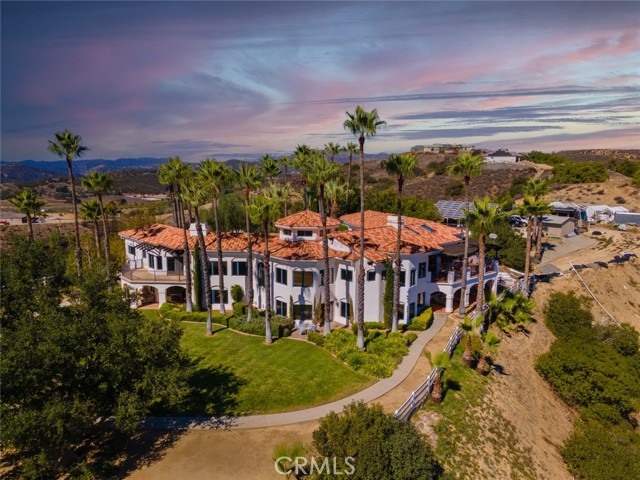 Located on the Santa Rosa Plateau, set off in the picturesque setting of La Cresta, secluded at the end of a cul-de-sac, hides this magical hillside resort! The main home features five bedrooms, six bathrooms, four fireplaces and views as far as the eye can see. Surrounded by more than 50 palm trees you ve got your own oasis privately tucked away on a hilltop all your own. The gentle driveway leads you through the 14+ acre property until you approach your private gated entry. This home includes two ensuites each with their own kitchen giving enough space for three families. Inside and outside staircases lead you throughout the 7100+ square-foot home. Terra-cotta tile at the entrance and throughout the kitchen give this home a warm and cozy feeling. Vaulted ceilings finished with rough sawn cedar wood beams at the entry ceiling and throughout the kitchen and family room. There is space for everyone and privacy on every floor. 6 A/C units throughout the home each with their separate controls. A kitchen to please any chef with a huge granite center island, double ovens, oversized subzero refrigerator, and storage space that makes you smile. The well produces over 120 gallons per minute. 5000 gallon propane tanks will last you throughout the year. The pool is heated by solar to keep your energy costs down. The Santa Rosa West association covers 1290 acres and each residence is a minimum of 10 acres. Plenty of fascinating wild life can be seen throughout the meadows off in the distance. This home is located just at Santa Rosa Wests' edge and no one can build to block your million dollar view. This association also has approximately 9 miles of horse trails for the equestrian enthusiast. Escape to this hidden Oasis in Santa Rosa West of La Cresta which is considered the hidden gem of Southern California.