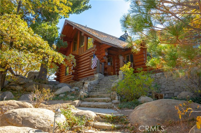 OWN A PIECE OF HISTORY! Originally owned by the film star Reginald Denny purchased in 1926. An actor in over 130 films and known as the  father  of the drone!! This custom built LOG HOME sits on over 6 acres with 180 degree views. Around the property you will find several out buildings that include 6 car garage, 3 car carriage house with possible apartment/granny flat upstairs, well house, and 2 storage sheds. BRING YOUR HORSES because a corral is also located on the property. The Main House features 2 beds, 2.5 bath, LOFT and BASEMENT that could be converted to 2 additional bedrooms! As you enter the home you are greeted by the stunning warm wood throughout. Cathedral ceilings made of massive wood beams with lots of natural light. The open living room is anchored by the original 1927 stone fireplace. The spacious kitchen boasts granite counters, stainless steel appliances, dining area with amazing views and a walk-in pantry/laundry room. Down the hallway is the master bedroom and bath with a walk-in shower. Opposite of the master is the second bedroom with built-in shelves. Just off the entry is the main floor powder room. Upstairs is a loft area with breathtaking picture windows and another full bathroom. This space could be converted to an additional bedroom. The basement includes a 3/4 bath with unfinished shower. Perfect space for an older child or relative. The expansive deck off the living room is original to 1927 along with the the stone entryway stairs leading to the front door and the stone walls around the base of the cabin. Store you car collection in the 6 car garage that features 220 volt along with heat and water. Across the driveway is the carriage house that could be used to store 3 more vehicles or used as a barn for animals. Upstairs is another living space not yet finished, that could be converted to an in-law suite or apartment. FEEL LIKE YOU ARE ON TOP OF THE WORLD! Located on a private GATED road, this property is one of a kind! 2 parcels are included in this sale. A 2-acre parcel sits below the home, perfect for a relative to build another house. See photos for more on the HISTORY of this amazing property.
