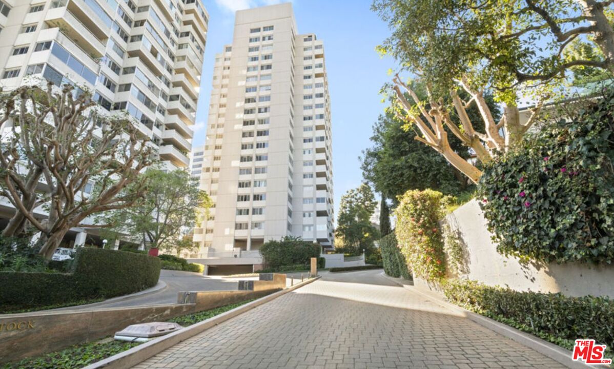 The Comstock condominium towers rise above a landscaped driveway and entrance.
